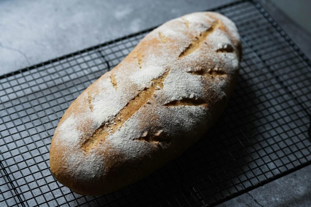 Delicious freshly baked sourdough bread with a crispy crust on a cooling rack in a cozy kitchen setting.