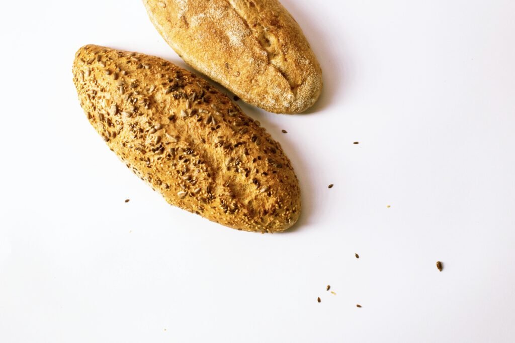 Two artisan loaves of bread with seeds, showcasing fresh baking, on a clean white backdrop.